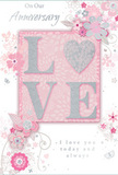 This anniversary card design unfolds like a quiet love story, beautifully composed in soft pastel pinks, pearly whites, and hints of silver that recall the gentle colours of early blossoms around Ilford in spring. At the centre, the word LOVE stands proudly in raised, glitter-touched letters, each character edged with a fine shimmer that glows rather than sparkles harshly, giving a sense of understated luxury. The letters are slightly embossed, offering a textured feel under the fingertips, just as the ridges of rose petals can be felt when arranging a bouquet for delivery across Ilford. Behind and around this central word, delicate illustrations of blossoms and trailing leaves stretch outward, their forms stylised yet clearly floral. They are drawn in fine lines of white and grey, softly shaded with blush and pale mauve, evoking the airy lightness of petals floating above the card's background. That background itself is a smooth field of gentle pink, deepening subtly near the centre and fading out towards the edges, creating depth like layers of tissue paper in a gift box. Tiny flourishes-curved tendrils, small petals, and almost-hidden butterflies-add movement and a sense of whimsy, as if the design is quietly alive. A refined script message offers anniversary wishes with sincerity, the flowing letters balancing perfectly with the floral scrolls. The result is a card that feels both modern and timeless, a paper keepsake as lovingly composed as a hand-tied posy, ideal for marking another shared year with grace and warmth in Ilford.